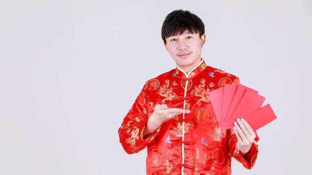 Un chinois chanceux portant une chemise mandarine traditionnelle sourit et se réjouit d'avoir reçu un cadeau culturel en espèces dans des enveloppes rouges lors des joyeuses fêtes de la prospérité pour le nouvel an lunaire