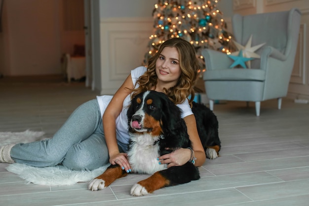 Un chiot berger écossais se trouve tranquillement sur le tapis près de l'hôtesse le soir du nouvel an.