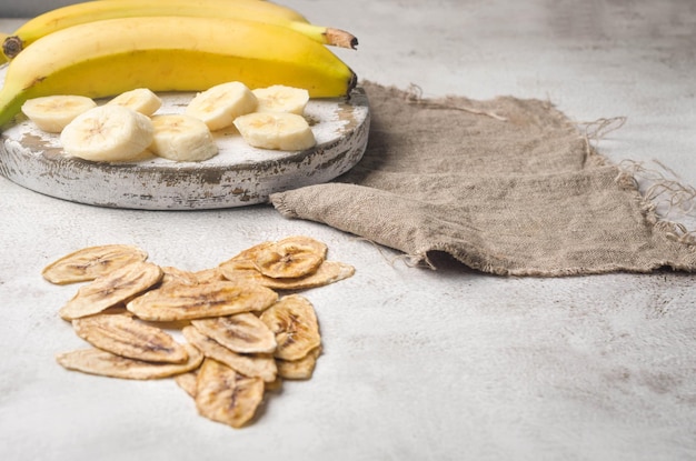 Chips de banane et de banane séchée éparpillées sur fond gris