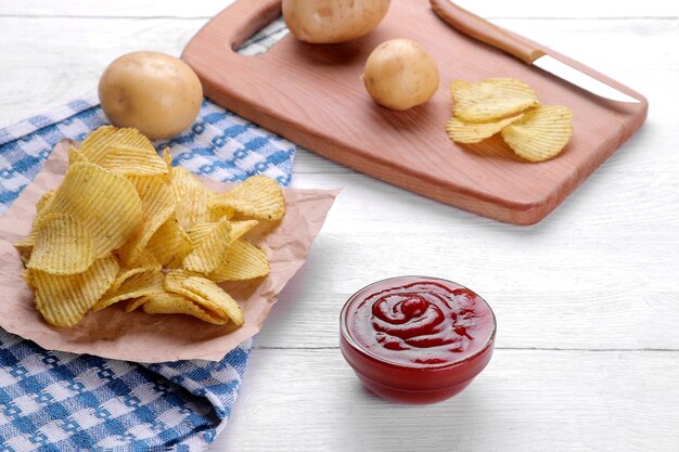 Chips, collations et sauce rouge sur une table en bois blanc