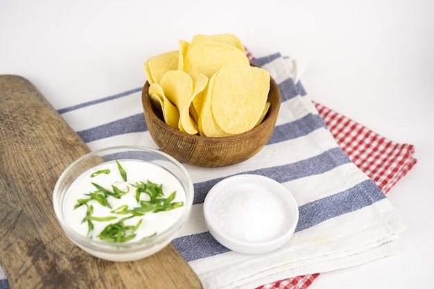 Chips dans un bol en bois avec crème sure et oignon vert