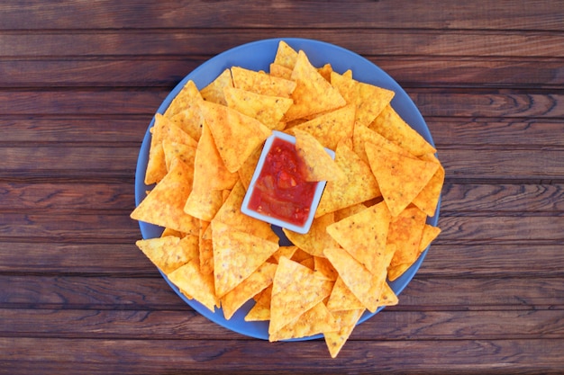 Chips de maïs Nachos dans un bol avec une sauce épicée sur un bois rustique