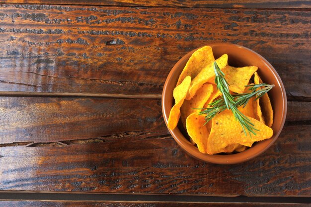 Chips de maïs nachos placés dans un bol en céramique sur une table en bois, espace de copie