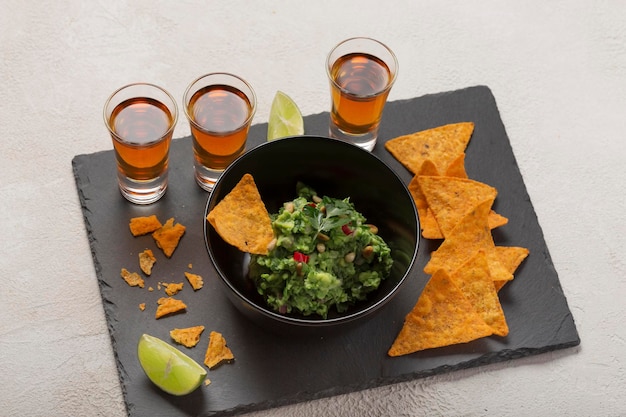 Chips de nachos avec guacamole et shots de tequila foncée ou de whisky