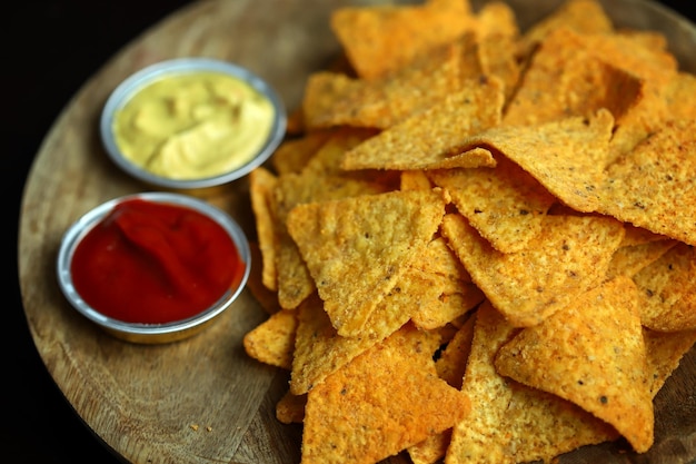 Chips de nachos avec sauces sur une planche de bois