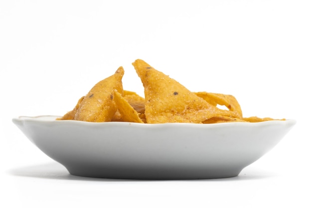 Photo des chips de nachos de tortilla de maïs croustillantes dans une petite assiette blanche isolée sur un chemin de coupe de fond blanc