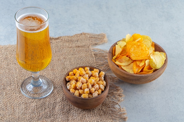 Chips de pois chiches et verre à bière sur une serviette en toile de jute , sur la surface en marbre.