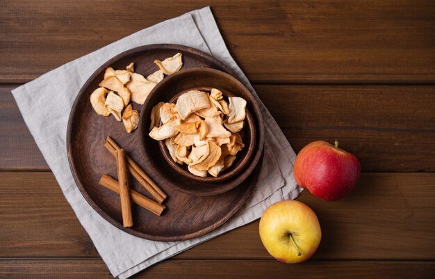 Chips de pommes maison sucrées cuites à la cannelle dans un bol en bois sur fond de bois. Produit végétalien et diététique