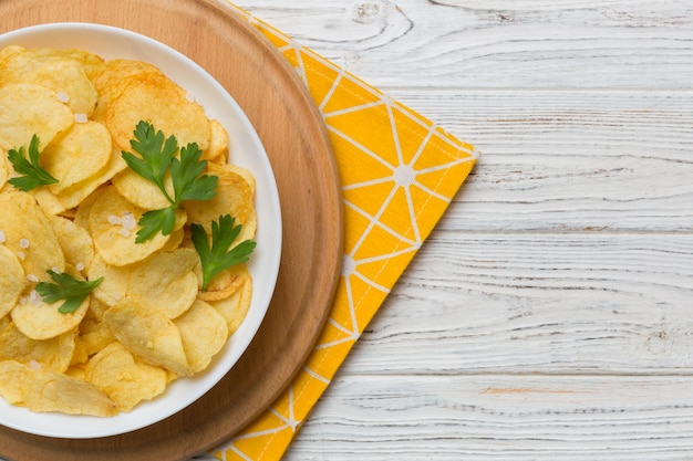 Chips de pommes de terre sur bol avec serviette sur fond coloré Délicieuses chips de pommes de terre croustillantes dans un bol Espace pour le texte Vue de dessus