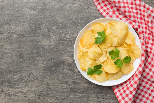 Chips de pommes de terre sur bol avec serviette sur fond coloré Délicieuses chips de pommes de terre croustillantes dans un bol Espace pour le texte Vue de dessus