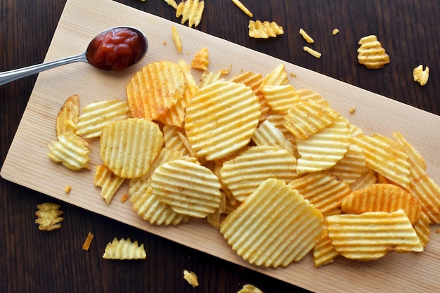 Chips de pommes de terre ou chips sur une planche à découper en bambou