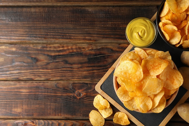 Chips de pommes de terre. Collations à la bière, sauce, pomme de terre sur une planche à découper, sur bois, espace pour le texte. Vue de dessus