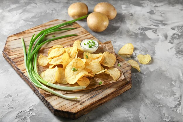 Chips de pommes de terre croustillantes à l'oignon vert et à la crème sure sur planche de bois