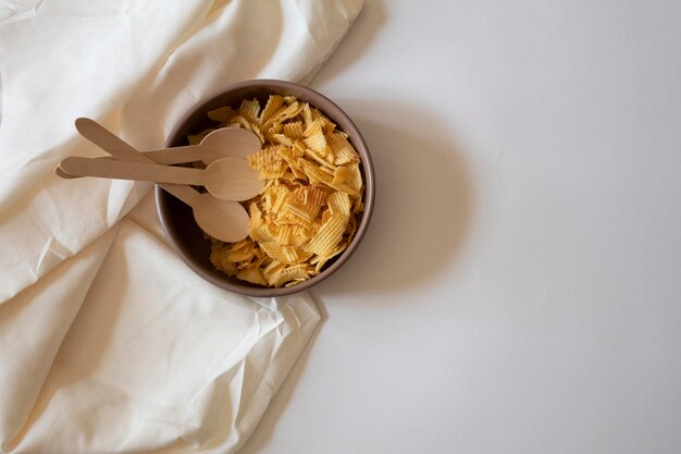 Chips de pommes de terre et cuillères sur fond blanc, pose plate minimale