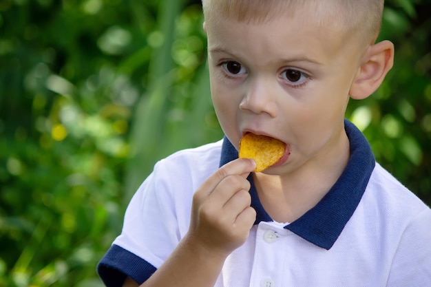 Chips de pommes de terre dans la main du garçon le garçon mange les frites mise au point sélective