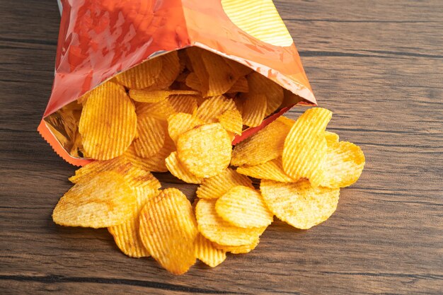 Photo des chips de pommes de terre délicieuses, des assaisonnements de barbecue, des épices pour les crips, des tranches minces, des friandises, des collations, des fast-foods dans un sac ouvert.