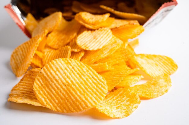 Des chips de pommes de terre délicieuses, des assaisonnements de barbecue, des épices pour les crips, des tranches minces, des friandises, des collations, des fast-foods dans un sac ouvert.