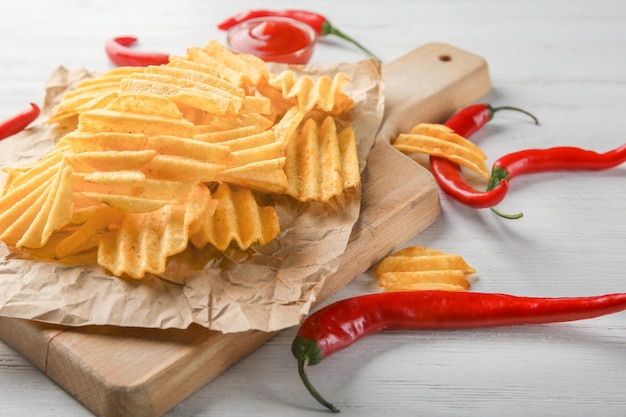 Chips de pommes de terre et piments sur planche de bois