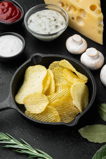 Chips de pommes de terre sertie de fromage et d'oignons avec de la crème sure sur fond de pierre noire