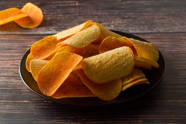 Chips de pommes de terre sur une table en bois. Snack croustillant salé.