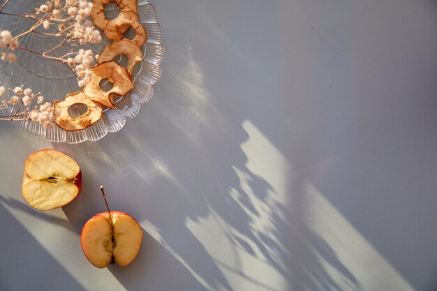 Des chips de pommes tranchées séchées saines des collations saines et des pommes fraîches sur l'assiette Ombres à la mode Vue de dessus Une bonne nutrition concept d'aliments sains Décoration de fleurs de gypsophile Photo de haute qualité