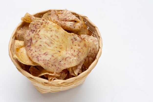 Chips de taro croustillantes dans un panier en bambou sur fond blanc.