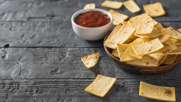 Chips d'une tortilla mexicaine à la sauce tomate sur la table en bois noire