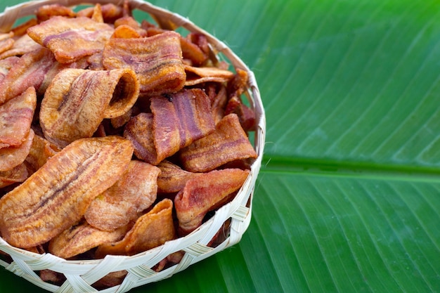 Chips de tranche de banane dans un panier en bambou sur une feuille de bananier