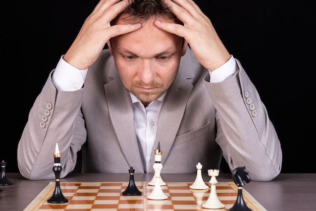 Échiquier avec homme d'affaires pensant à la stratégie d'échecs