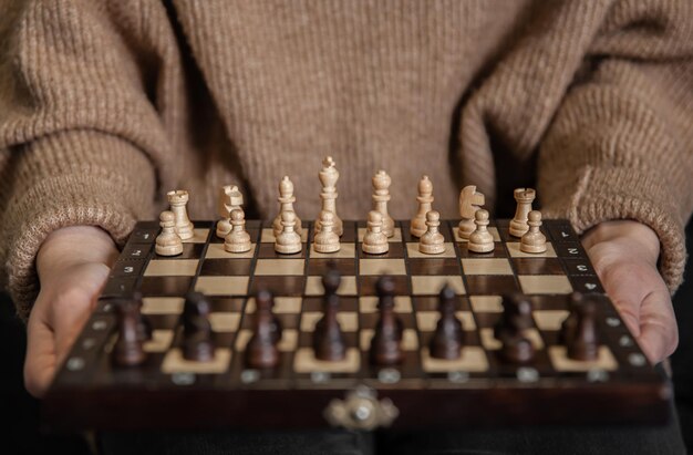 Échiquier avec des pièces d'échecs en bois dans des mains féminines