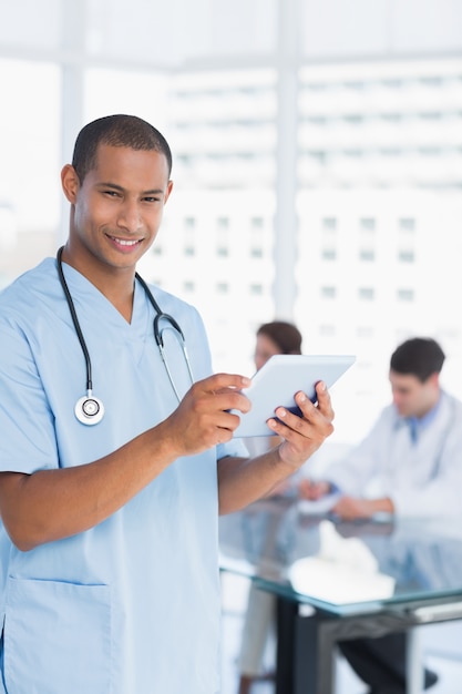 Chirurgien à l&#39;aide de tablette numérique avec groupe autour de la table à l&#39;hôpital