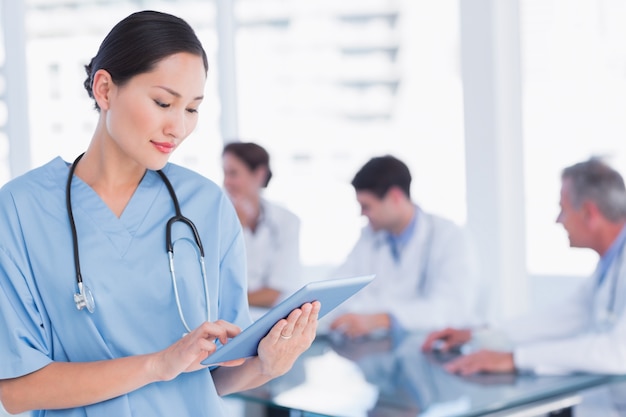 Chirurgien à l&#39;aide de tablette numérique avec groupe autour de la table à l&#39;hôpital