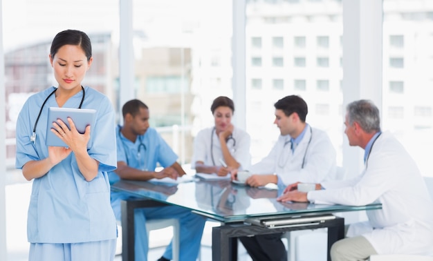 Chirurgien à l&#39;aide de tablette numérique avec groupe autour de la table à l&#39;hôpital