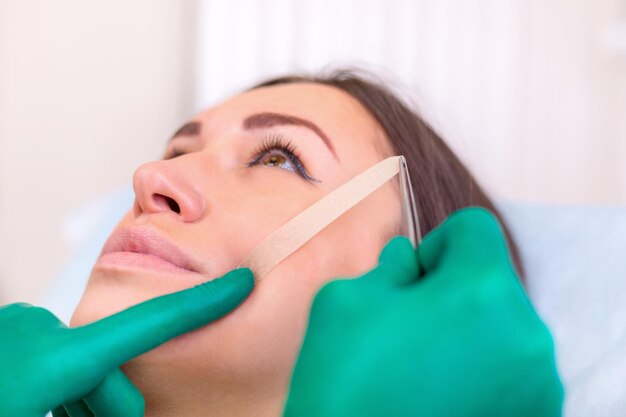 Chirurgien esthétique examinant une cliente au bureau Médecin vérifiant le visage de la femme la paupière avant la chirurgie plastique blépharoplastie Chirurgien ou esthéticienne mains touchant le visage de la femme Rhinoplastie