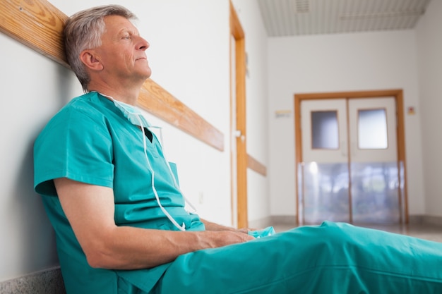 Chirurgien fatigué est assis sur le sol dans le couloir de l&#39;hôpital