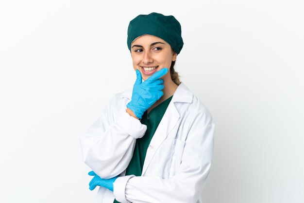 Chirurgien femme caucasienne isolée sur fond blanc regardant sur le côté et souriant