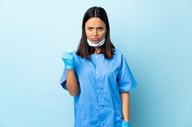 Chirurgien femme sur mur bleu avec expression malheureuse