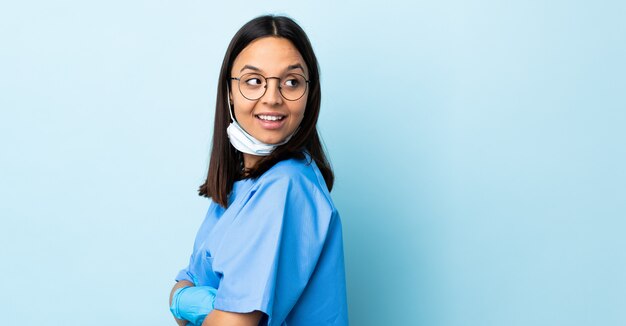 Chirurgien femme sur mur bleu isolé avec les bras croisés et heureux