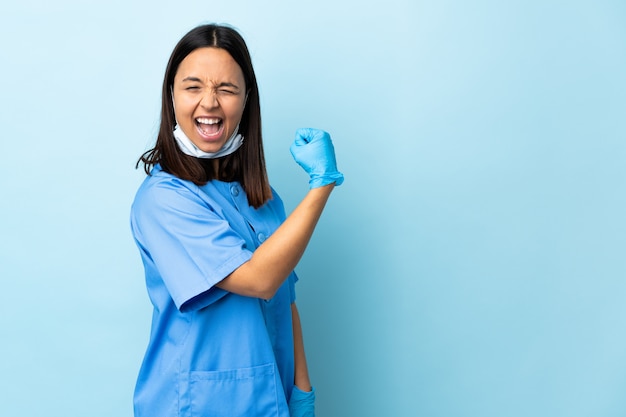 Chirurgien femme sur mur bleu isolé célébrant une victoire