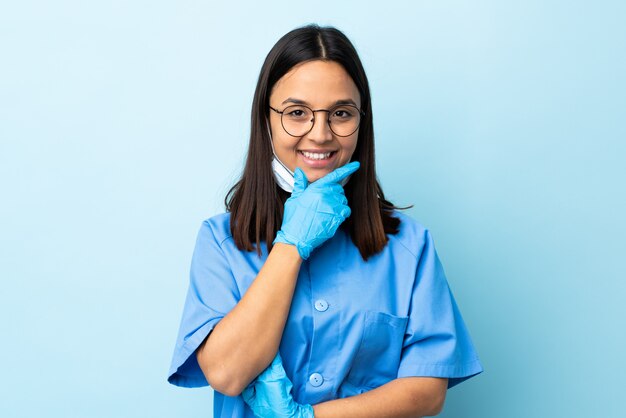 Chirurgien femme sur mur bleu isolé heureux et souriant