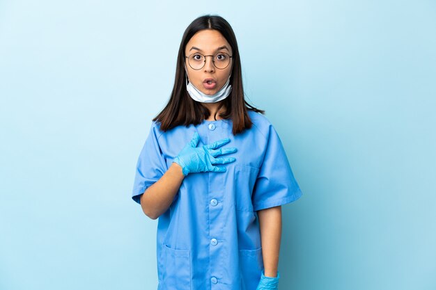 Chirurgien femme sur mur bleu surpris et choqué tout en regardant à droite