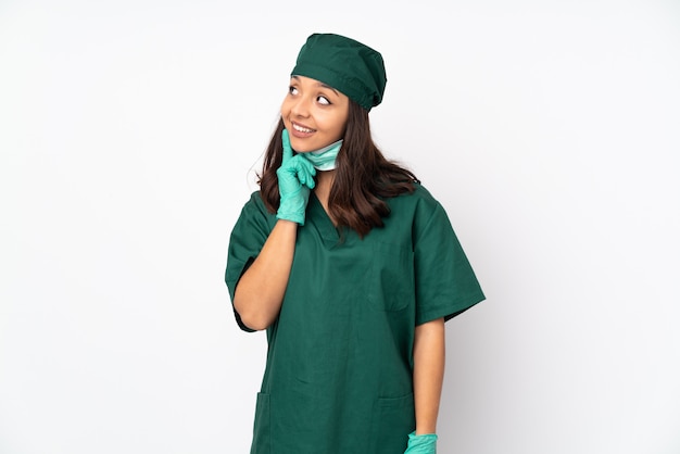 Chirurgien Femme En Uniforme Vert Sur Blanc En Pensant à Une Idée Tout En Levant