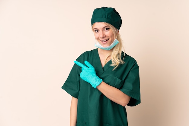 Chirurgien femme en uniforme vert sur mur isolé doigt pointé sur le côté