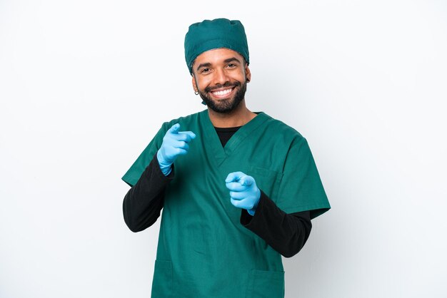 Chirurgien homme brésilien en uniforme vert isolé sur fond blanc pointant vers l'avant et souriant