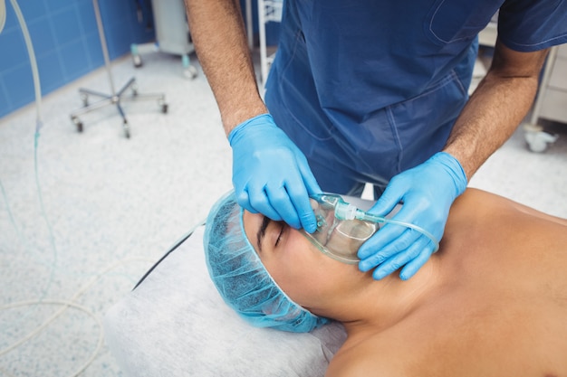 Chirurgien mâle mettant un masque à oxygène sur le patient