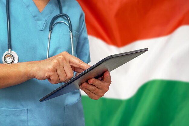 Chirurgien ou médecin à l'aide d'une tablette numérique sur le fond du drapeau de la Hongrie