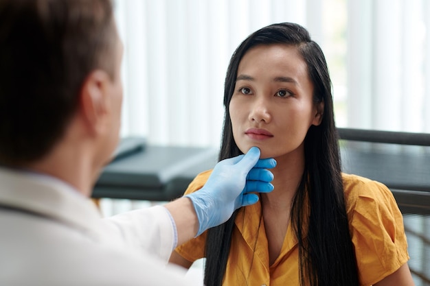 Un chirurgien plasticien examine le visage d'une femme avant de lui recommander un traitement.