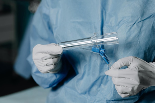 Un chirurgien portant des gants en latex et un uniforme bleu tient un instrument proctologique spécial