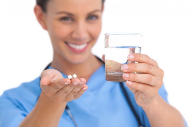 Chirurgien souriant, tenant des médicaments et un verre d&#39;eau