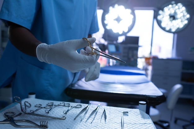 Photo chirurgien tenant des ciseaux chirurgicaux dans la salle d'opération d'un hôpital